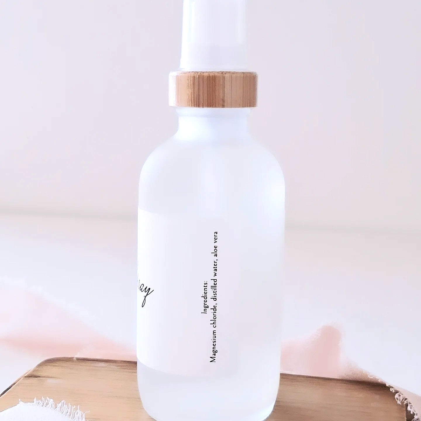 White bottle with a wooden cap on a light pink background